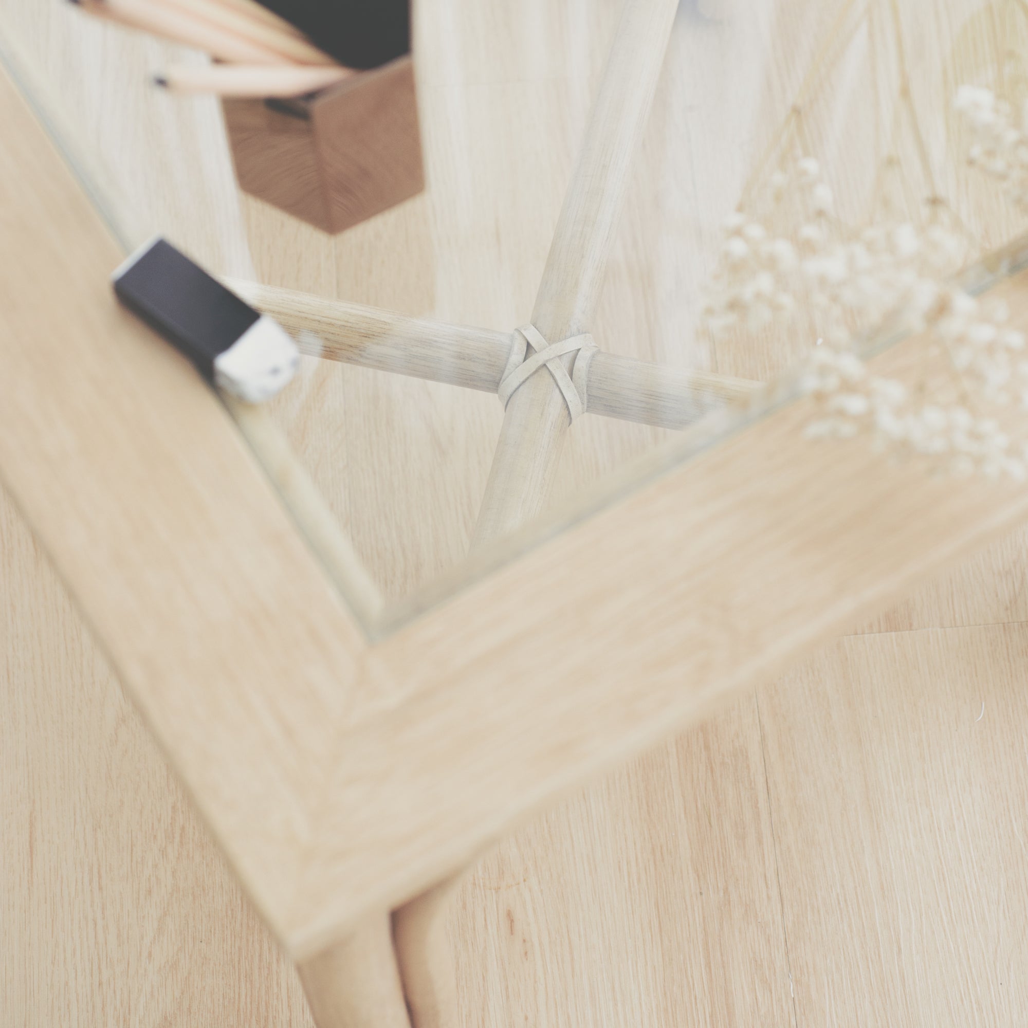 Close-up on the tempered glass surface of the handcrafted cane side table. Its tempered glass top provides an easy-to-clean surface, making it ideal for everyday use. It also bounces light off, creating an open impression.
