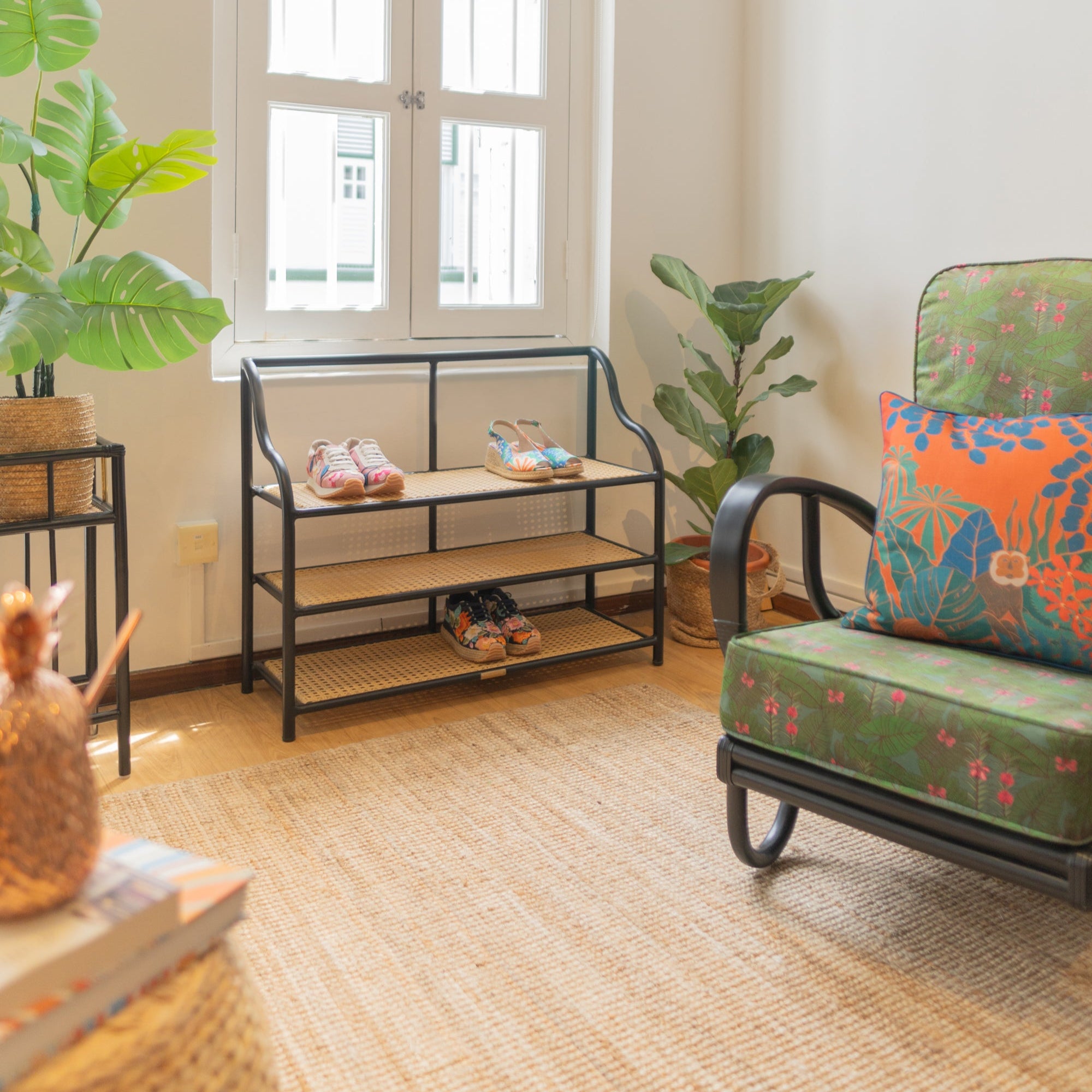 An elegant bent metal shoe rack with synthetic wicker details in a light filled shophouse in Singapore