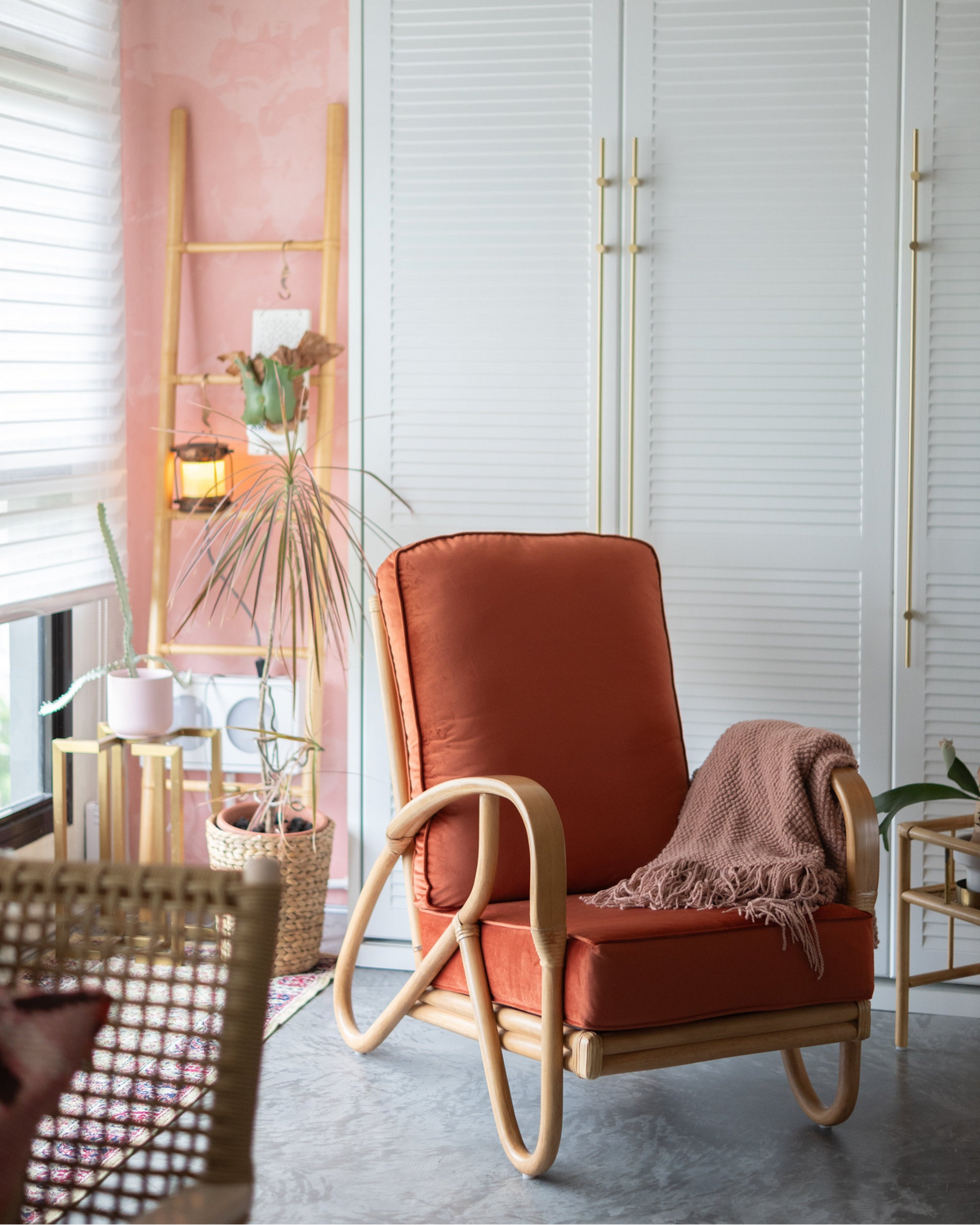 A cane armchair with brick red upholstery in a living room