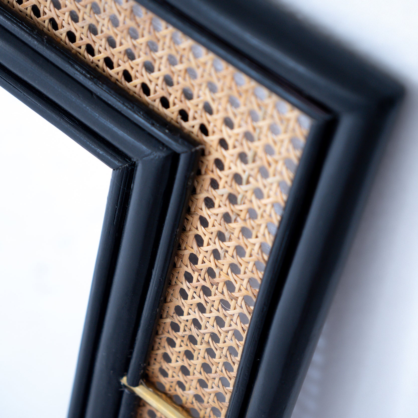 Black rattan mirror with a handcrafted frame, combining natural texture and modern design. Its sleek finish and minimalist aesthetic make it a versatile statement piece for any room. Designed in Singapore, it reflects timeless elegance with a touch of heritage charm.
